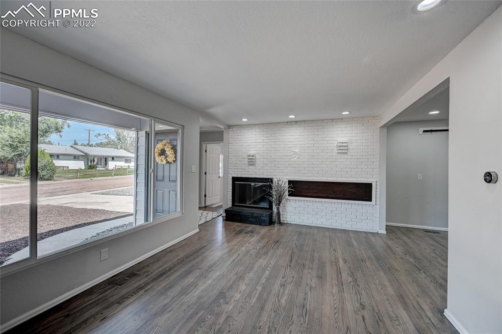 505 Inca Drive Colorado Springs, CO 80911 - Photo 3 of 33 a view of empty room with wooden floor and fireplace