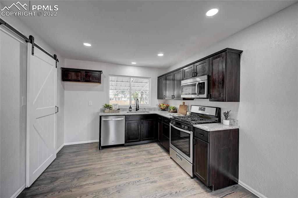 505 Inca Drive Colorado Springs, CO 80911 - Photo 8 of 33 a kitchen with stainless steel appliances granite countertop a stove top oven a sink dishwasher a refrigerator and a microwave oven with wooden floor
