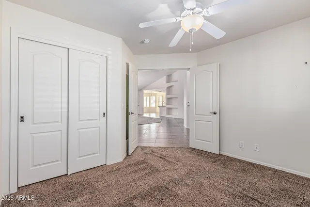an empty room with chandelier fan and closet area
