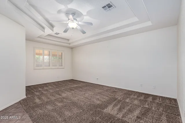 an empty room with a chandelier fan and windows