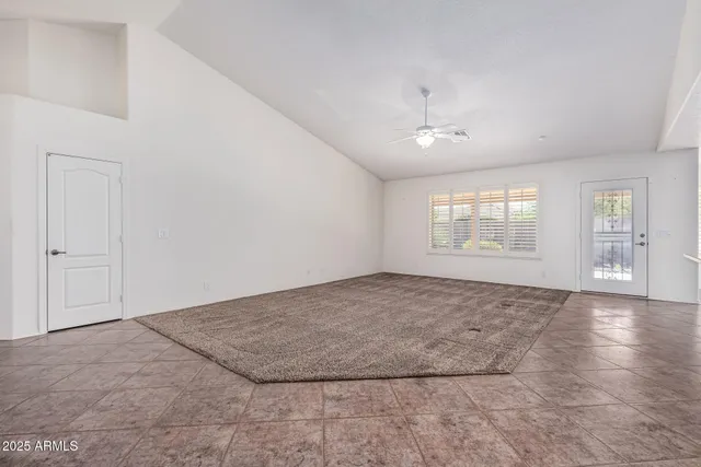 an empty room with windows and ceiling fan