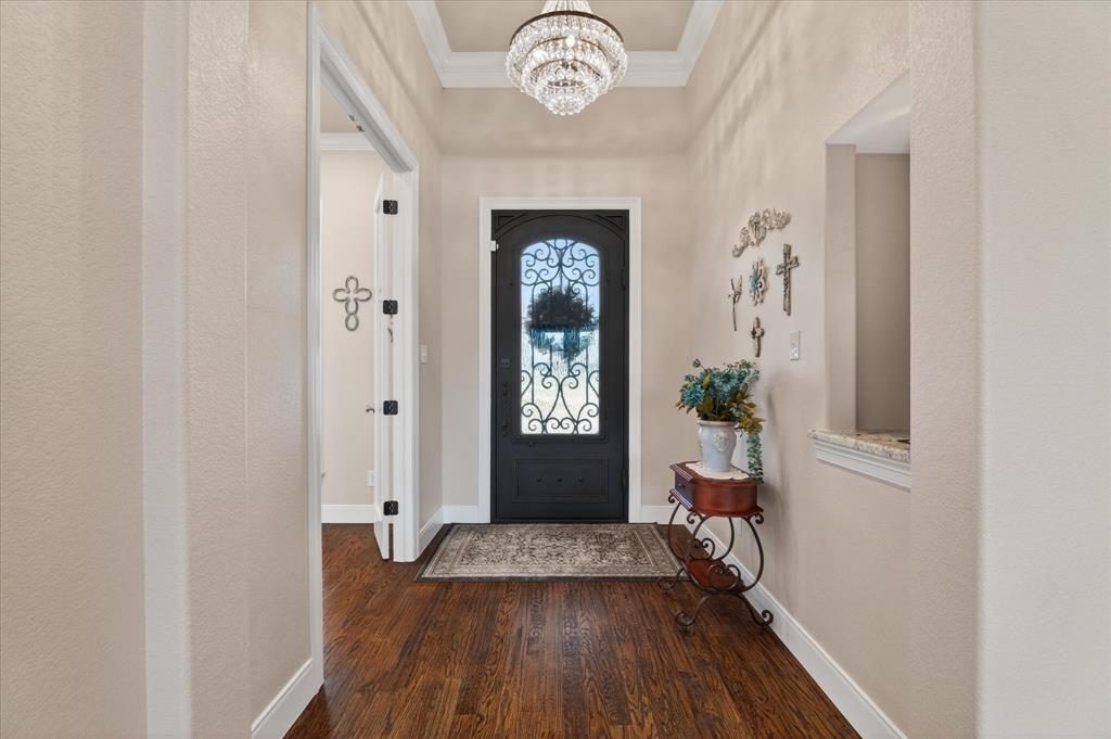 790 Bones Chapel Road Whitesboro, TX 76273 - Photo 8 of 39 a hallway with front door wooden floor and a chandelier