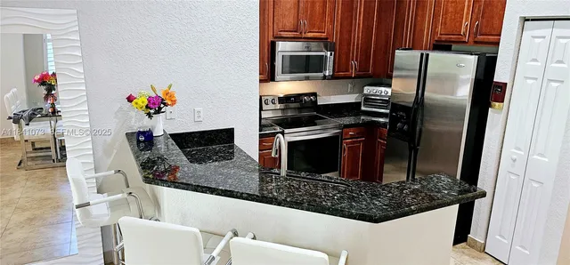 a kitchen with stainless steel appliances granite countertop a refrigerator and a stove top oven