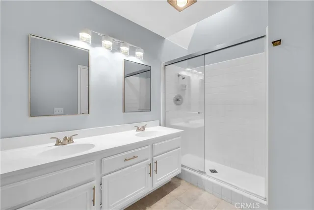 a bathroom with a double vanity sink mirror and shower