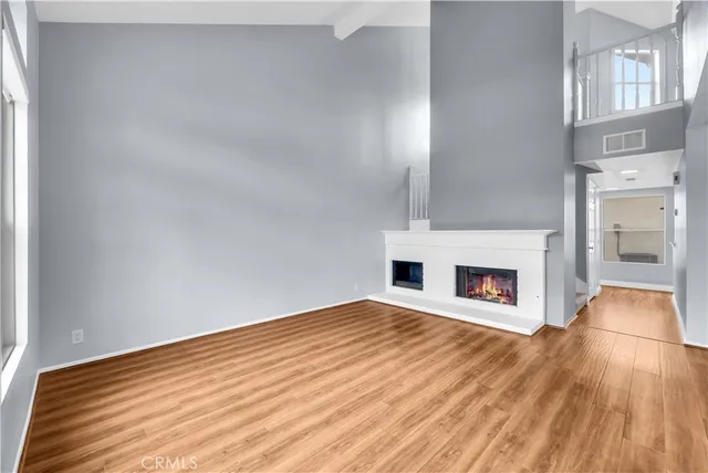 a view of empty room with fireplace and wooden floor