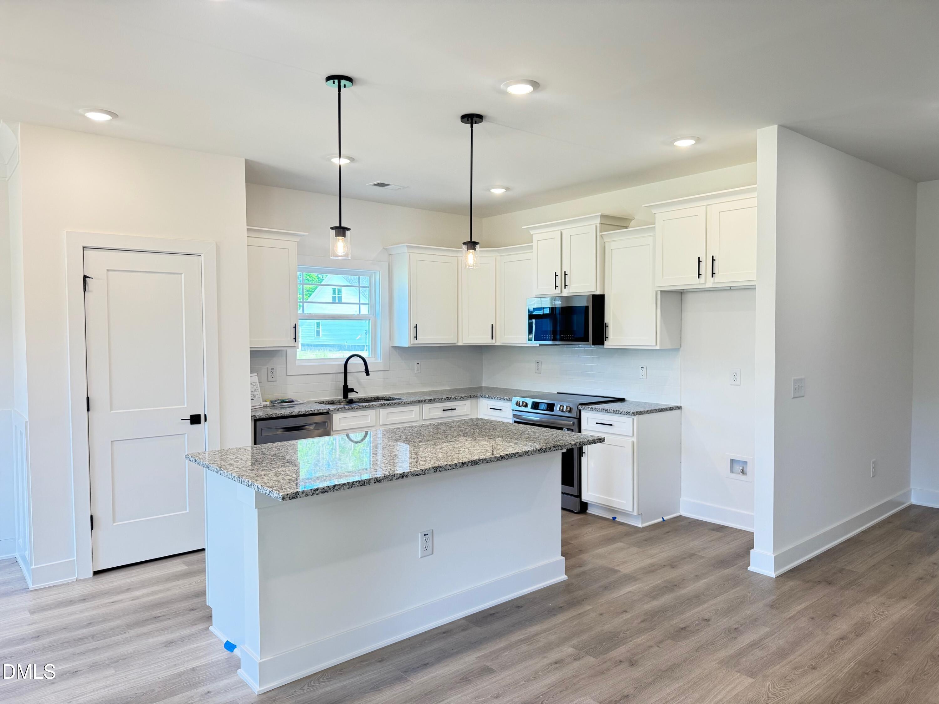 20 Streamline Court Lillington, NC 27546 - Photo 17 of 46 a kitchen with stainless steel appliances granite countertop a sink a stove a refrigerator and island with wooden floor
