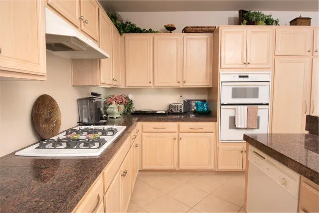a kitchen with granite countertop a stove a sink and a refrigerator