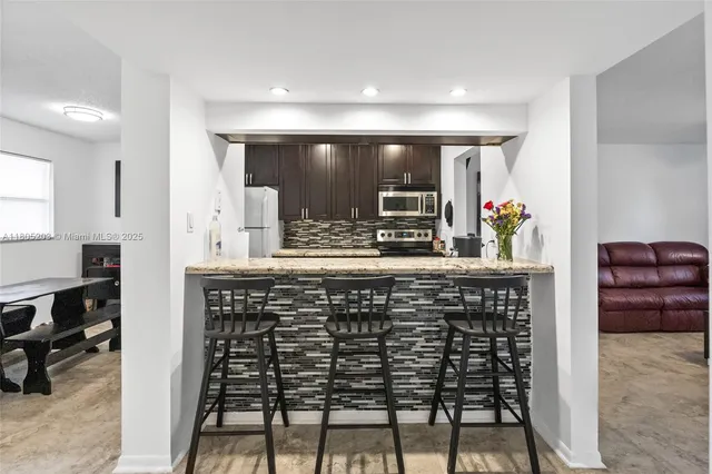 a kitchen with stainless steel appliances kitchen island granite countertop a sink and a refrigerator