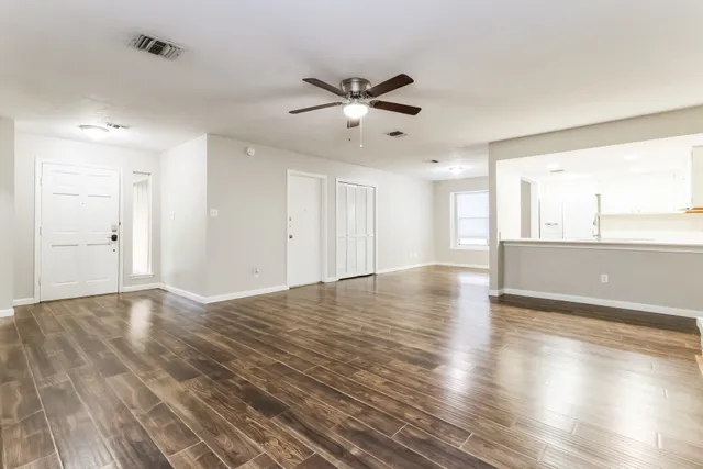 a view of an empty room with window and wooden floor