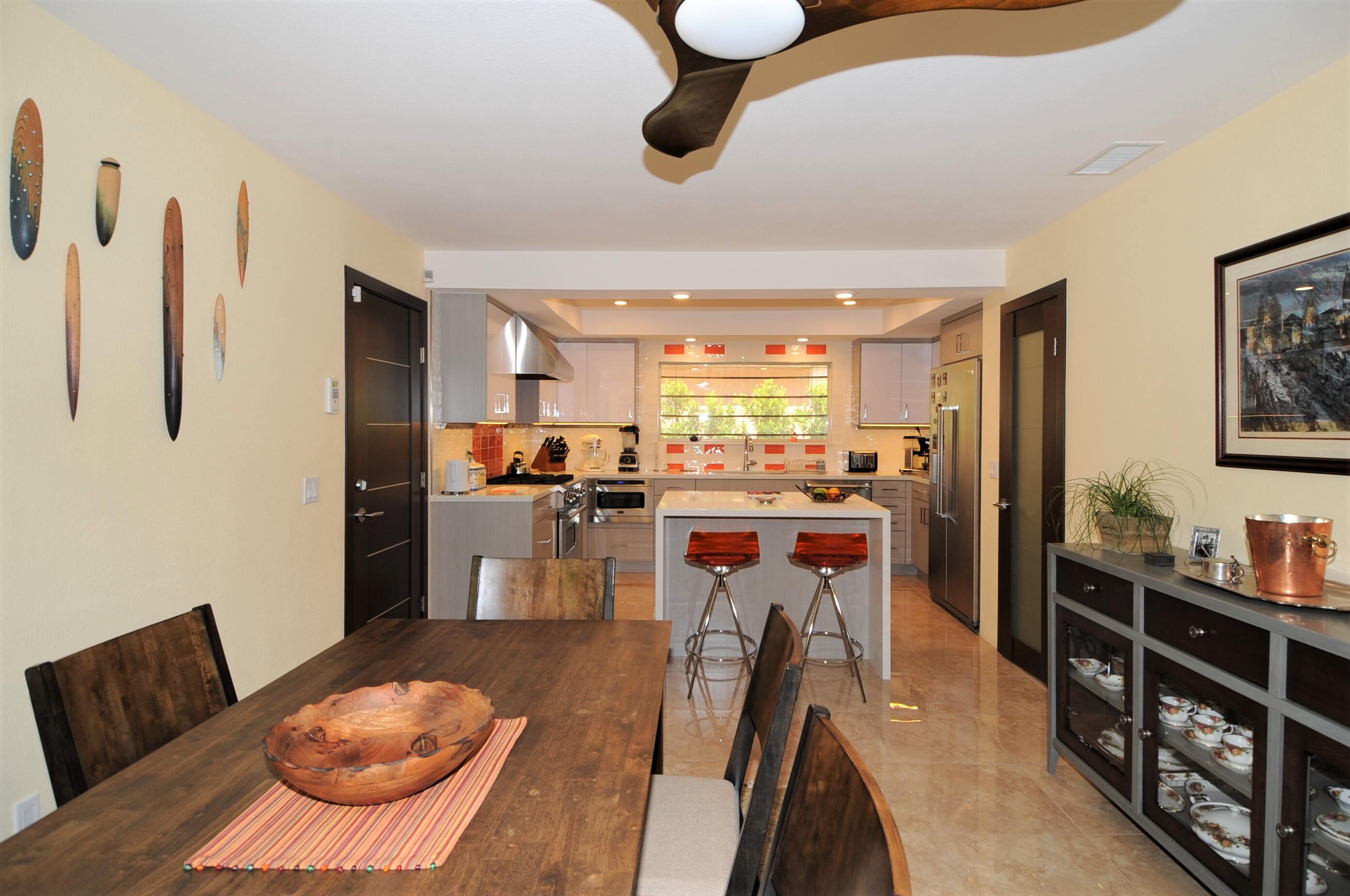 1490 East Racquet Club Road Palm Springs, CA 92262 - Photo 11 of 29 a kitchen with stainless steel appliances kitchen island granite countertop a refrigerator a stove a sink a dining table and chairs with wooden floor