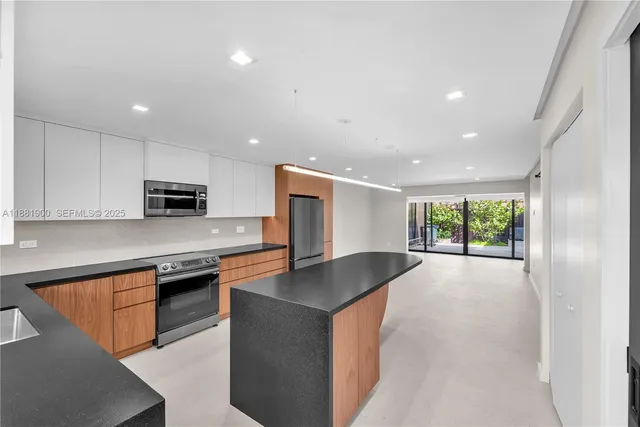 a kitchen with stainless steel appliances granite countertop a sink dishwasher a stove and a refrigerator with wooden floor