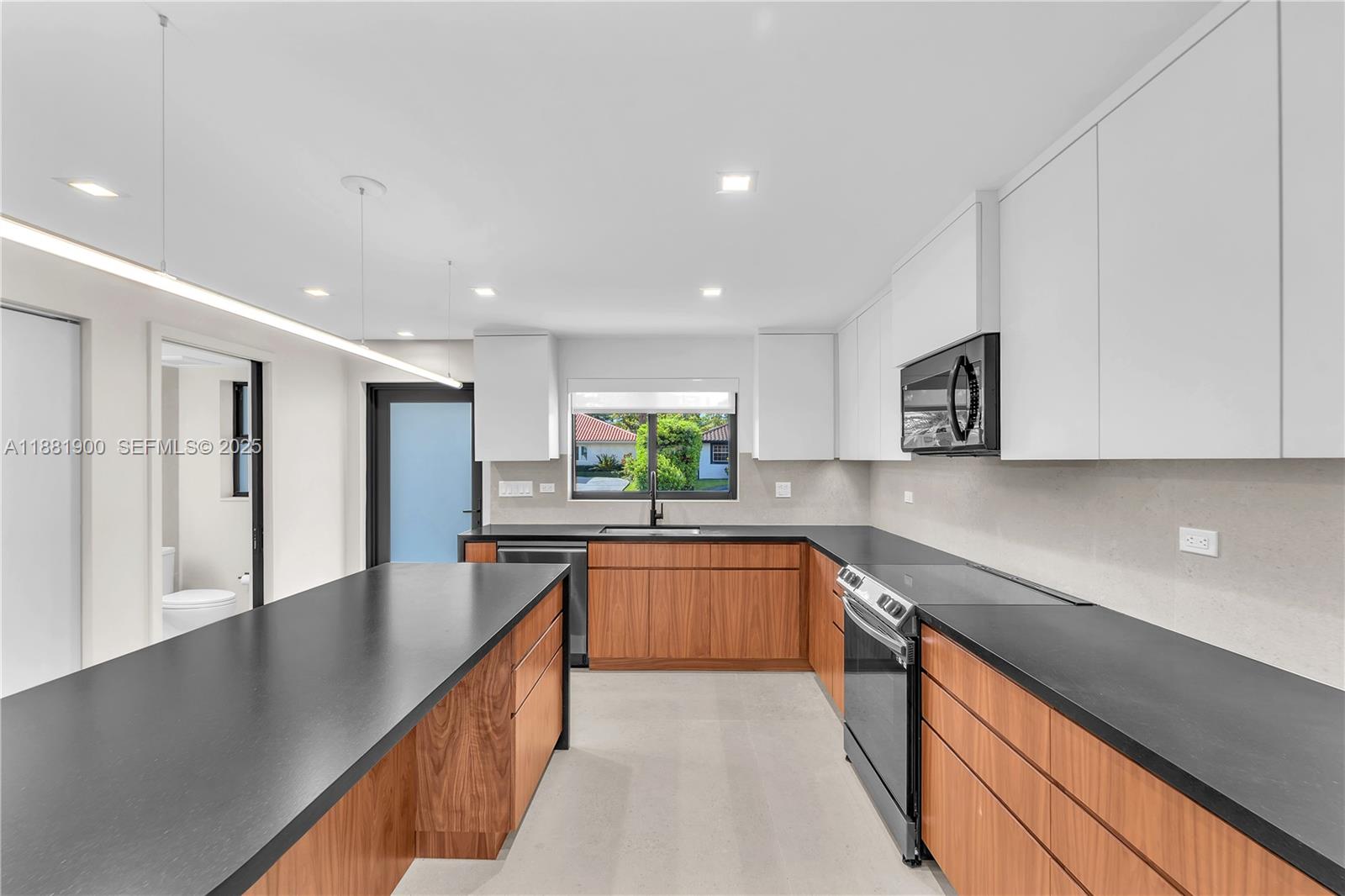 2211 Northeast 122nd Street, Unit 2211 North Miami, FL 33181 - Photo 6 of 34 a large kitchen with stainless steel appliances granite countertop a lot of counter space and wooden floor