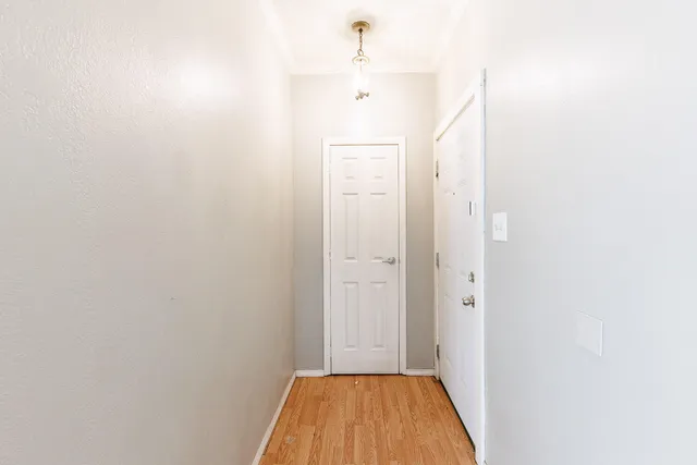 a view of a hallway with wooden floor and a bathroom