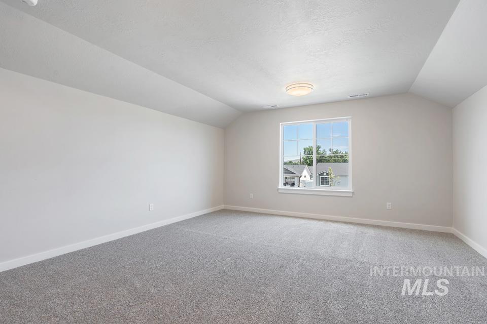 1355 Crescent Street Weiser, ID 83672 - Photo 25 of 31 Additional living space with vaulted ceiling, carpet, and a textured ceiling