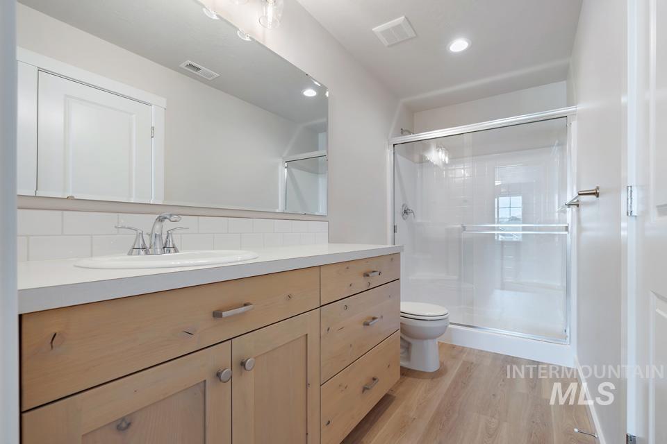 1355 Crescent Street Weiser, ID 83672 - Photo 27 of 31 Bathroom featuring vanity, wood finished floors, a shower stall, decorative backsplash, and recessed lighting