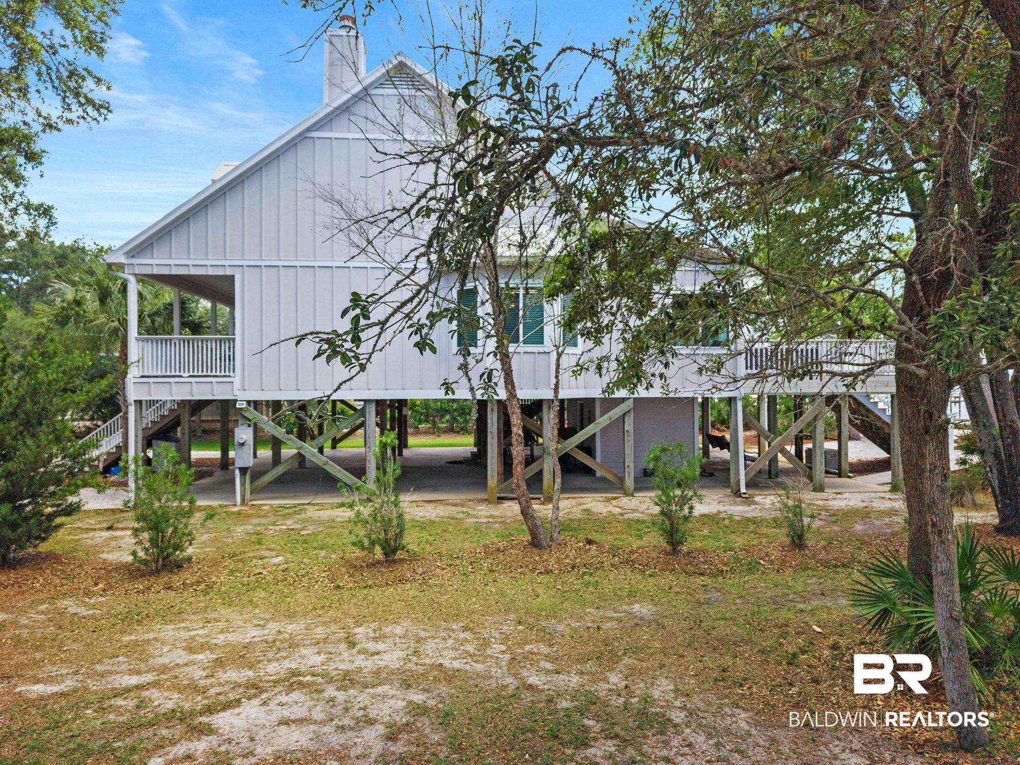6802 Shore Drive Elberta, AL 36530 - Photo 2 of 34 Elevated residence featuring board and batten siding, multiple balconies with white railings, and a prominent chimney