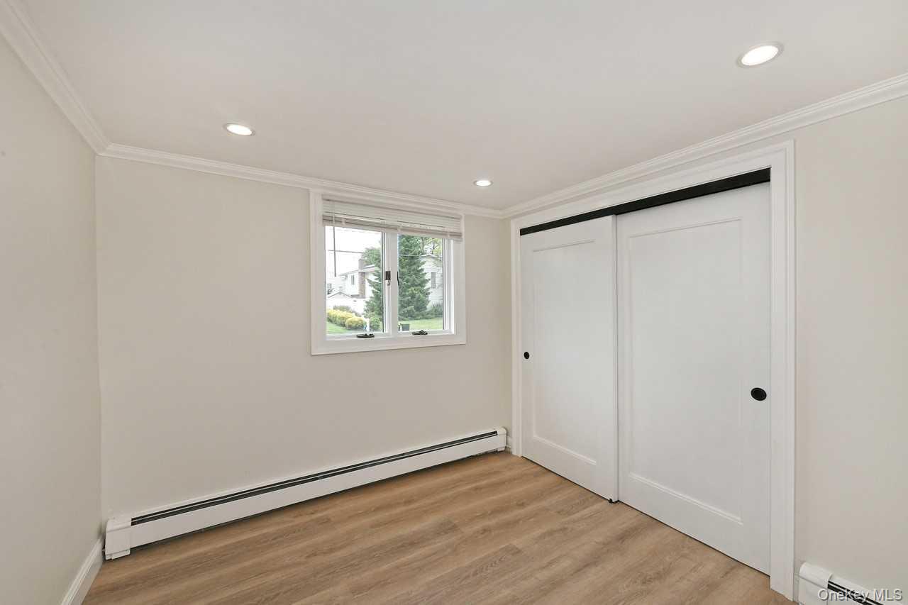 107 Beverly Road Massapequa, NY 11758 - Photo 20 of 41 a view of an empty room with wooden floor and a window