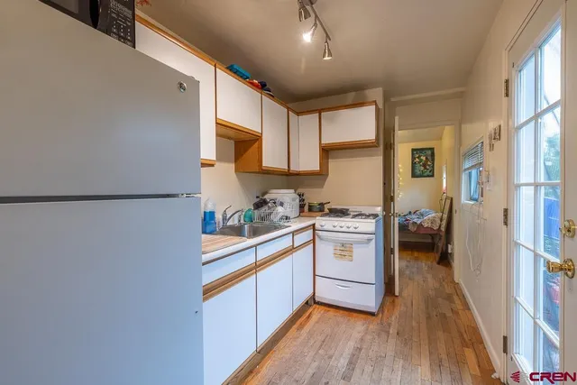 a kitchen with stainless steel appliances granite countertop a refrigerator a sink dishwasher a stove and white countertops with wooden floor