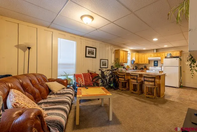 a living room with furniture kitchen view and a large window