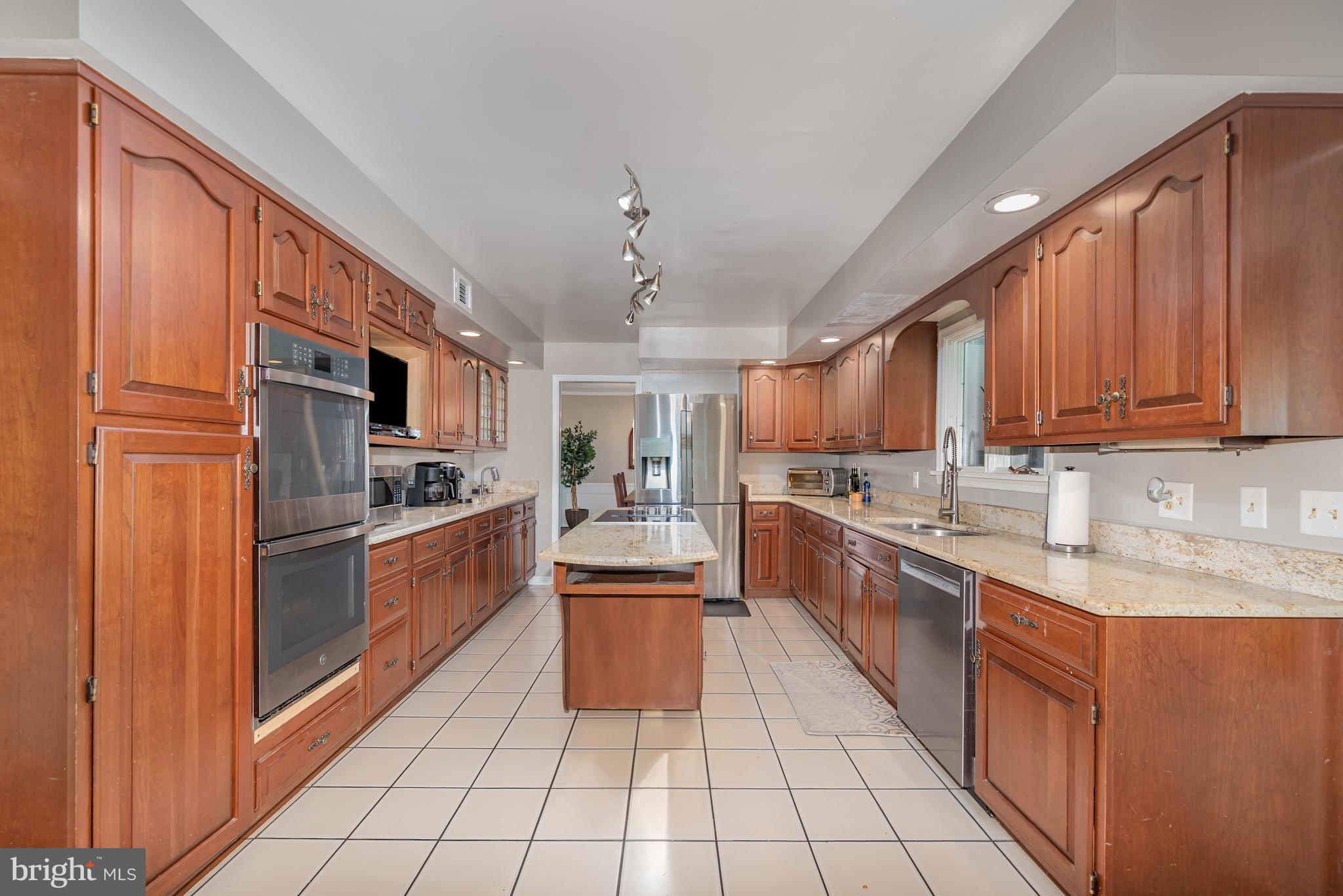 5214 Forge Road Perry Hall, MD 21128 - Photo 11 of 35 a large kitchen with stainless steel appliances granite countertop a stove top oven a sink dishwasher a dining table and chairs with wooden floor