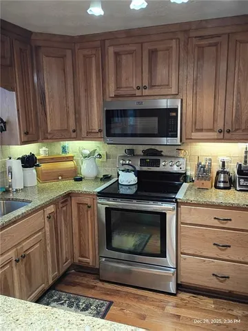 a kitchen with granite countertop a stove top oven microwave and cabinets