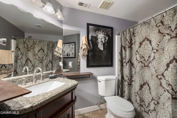 a bathroom with a granite countertop toilet sink and mirror