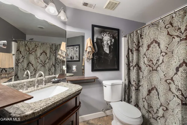 a bathroom with a granite countertop toilet sink and mirror