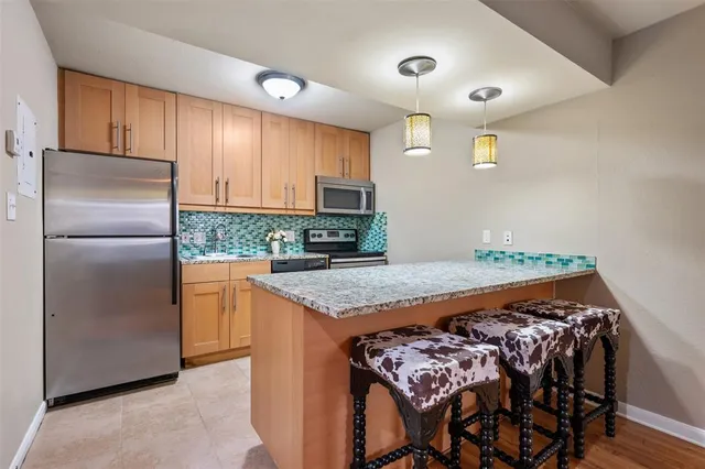 a kitchen with stainless steel appliances granite countertop a stove a sink and a refrigerator