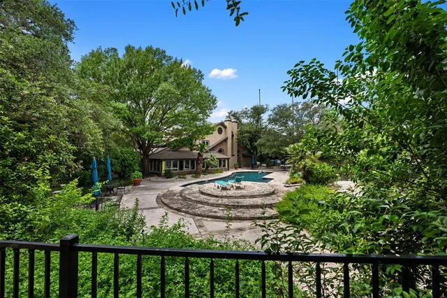 a view of backyard with table and chairs potted plants and a large tree