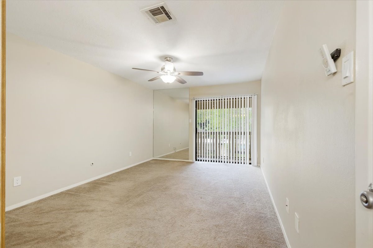 3502 Ocee Street, Unit 3502 Houston, TX 77063 - Photo 15 of 28 This room features neutral-colored walls and carpet, a ceiling fan with light, and sliding glass doors leading to a small balcony with vertical blinds. It offers a clean and bright space with potential for customization.