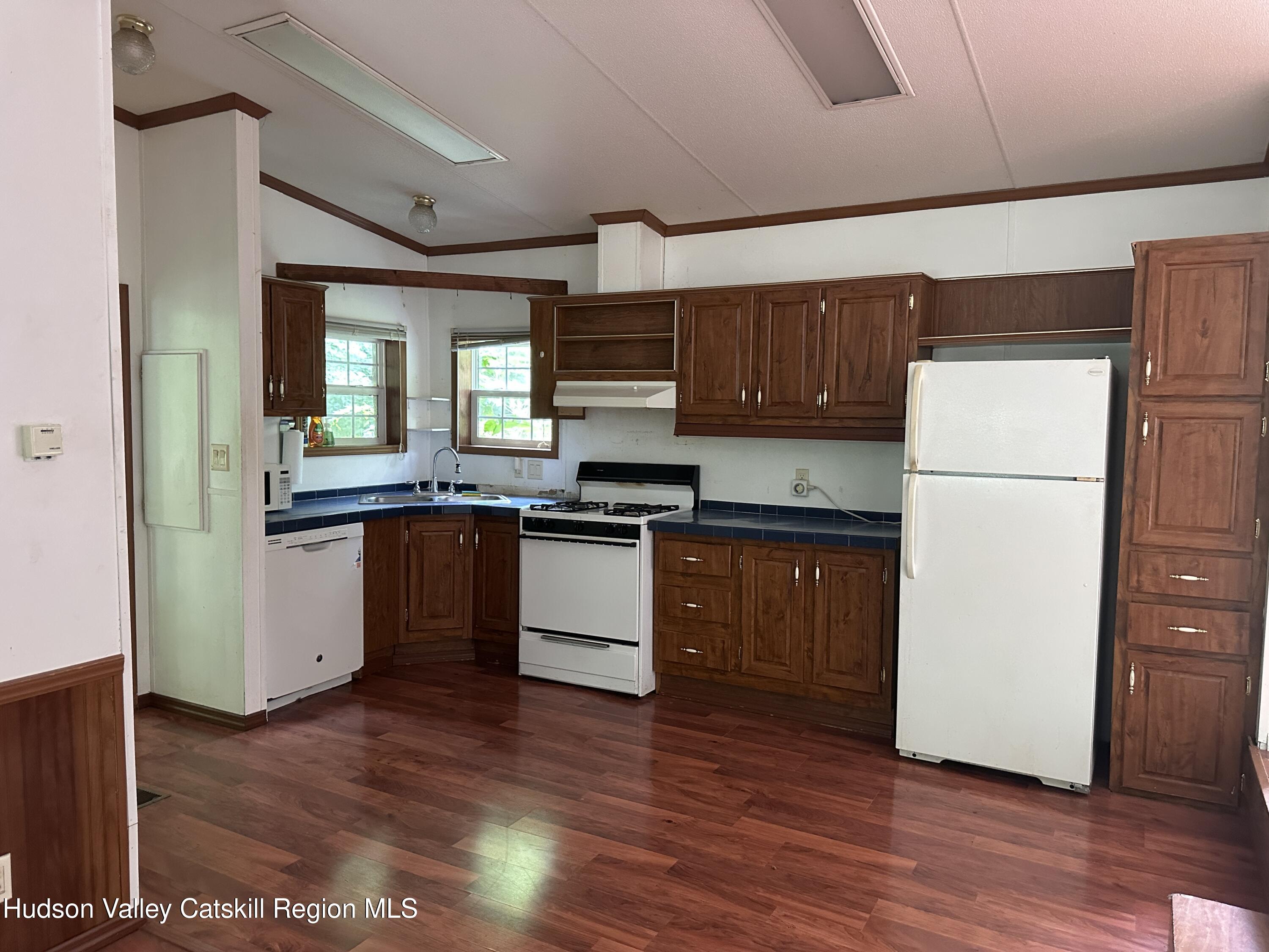 166 Falls View Lane Purling, NY 12470 - Photo 12 of 26 a kitchen with granite countertop wooden floors a refrigerator a sink and white cabinets