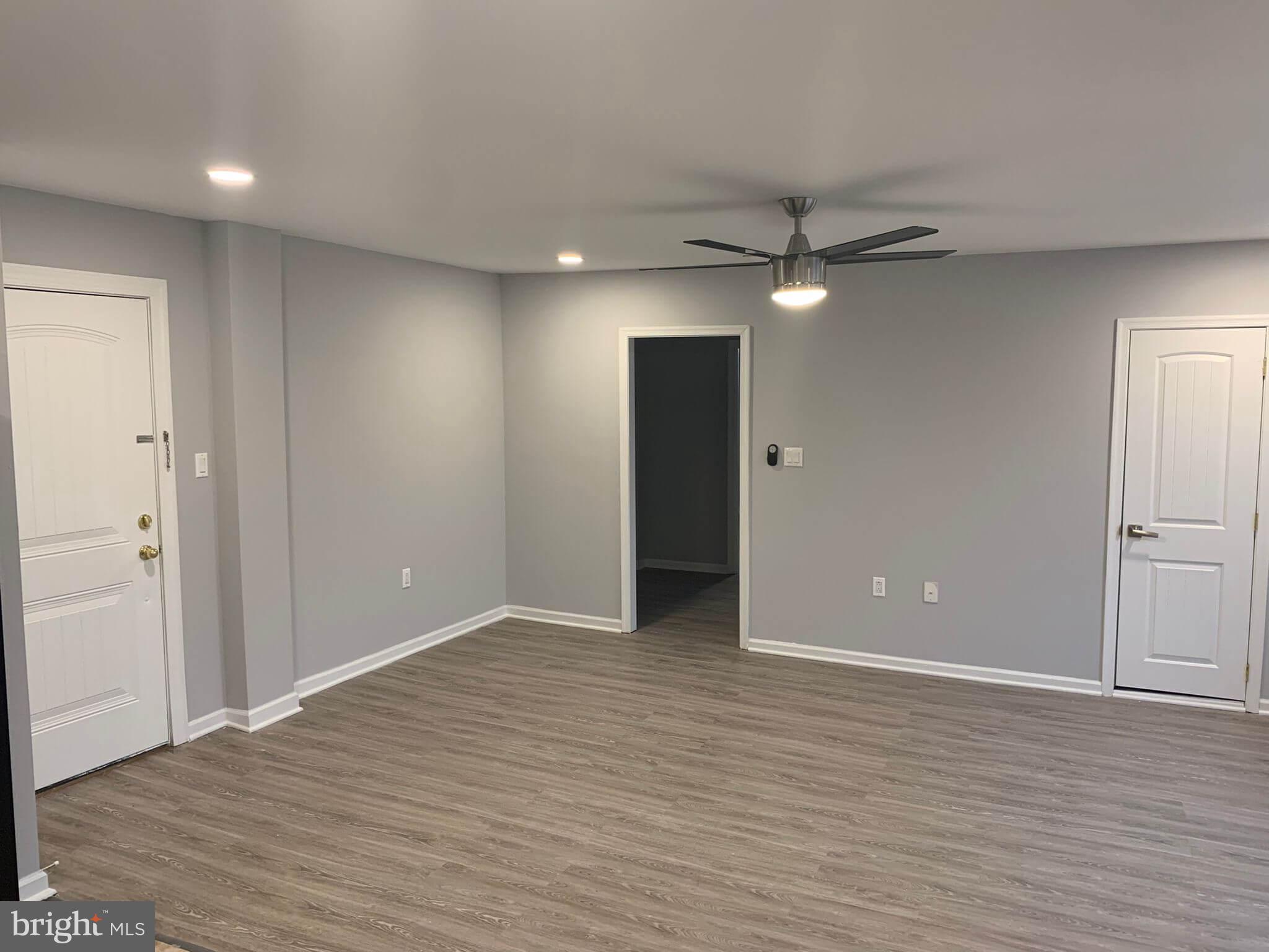 an empty room with wooden floor and a ceiling fan