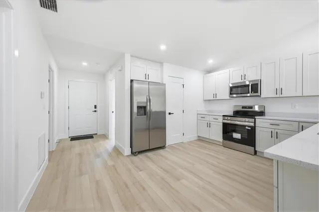 a kitchen with granite countertop a refrigerator and a stove top oven