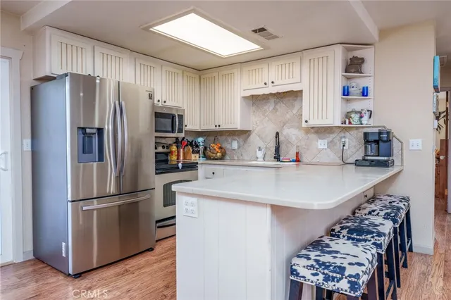 a kitchen with stainless steel appliances a sink a refrigerator and cabinets