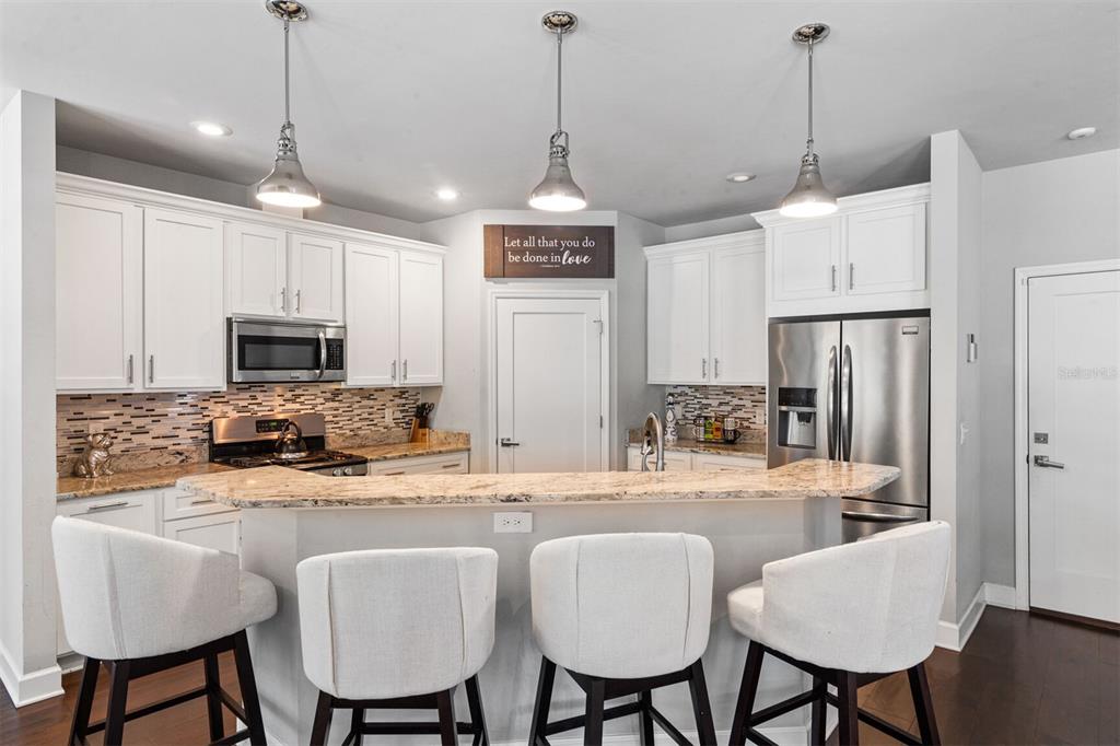 4855 Southwest 64th Road Gainesville, FL 32608 - Photo 16 of 44 a kitchen with stainless steel appliances kitchen island granite countertop a dining table chairs refrigerator and sink
