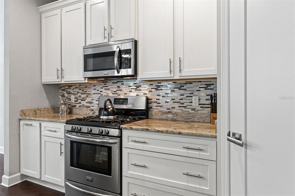 4855 Southwest 64th Road Gainesville, FL 32608 - Photo 19 of 44 a kitchen with granite countertop white cabinets and stainless steel appliances