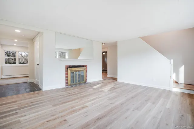 a view of empty room with wooden floor and fireplace