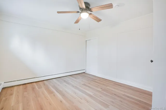 an empty room with a ceiling fan and wooden floor