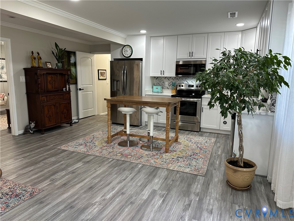 305 Myrtle Street, Unit A Ashland, VA 23005 - Photo 33 of 59 a kitchen with stainless steel appliances kitchen island granite countertop a refrigerator a stove a microwave oven a dining table and chairs with wooden floor