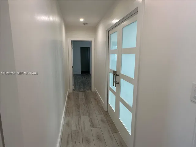 a view of a hallway with wooden floor and a bathroom