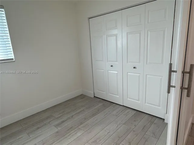 a view of an empty room with closet and wooden floor