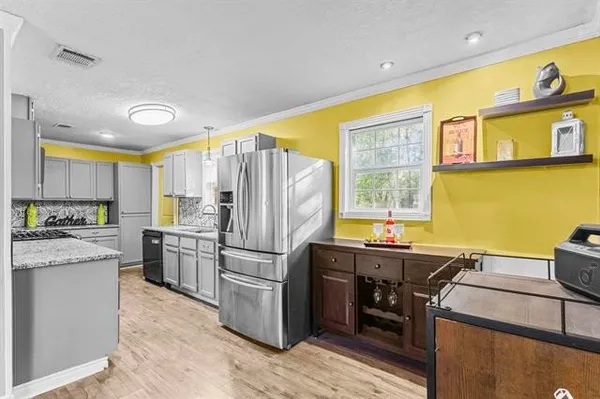 a kitchen with stainless steel appliances kitchen island granite countertop a refrigerator a stove top oven and a dining table with wooden floor