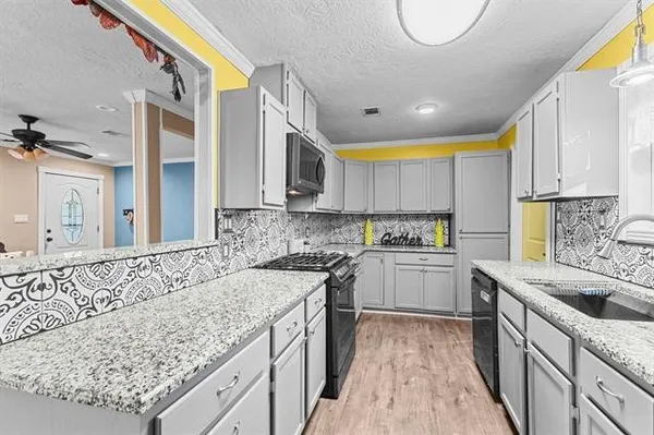 a kitchen with granite countertop a sink a counter space stainless steel appliances and cabinets