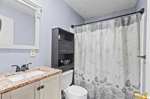 a bathroom with a granite countertop sink toilet and shower