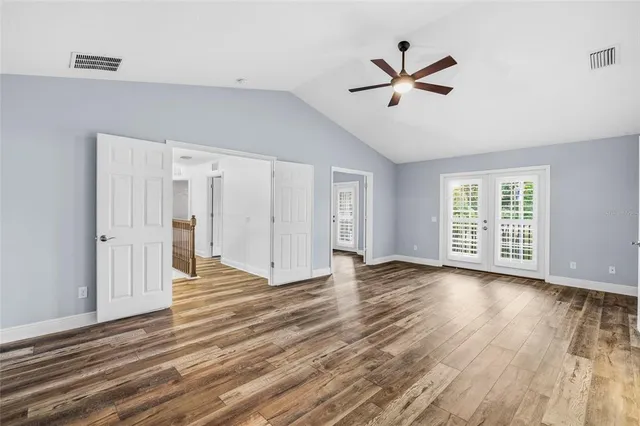 a view of empty room with wooden floor and fan