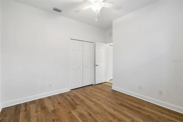 an empty room with wooden floor and fan