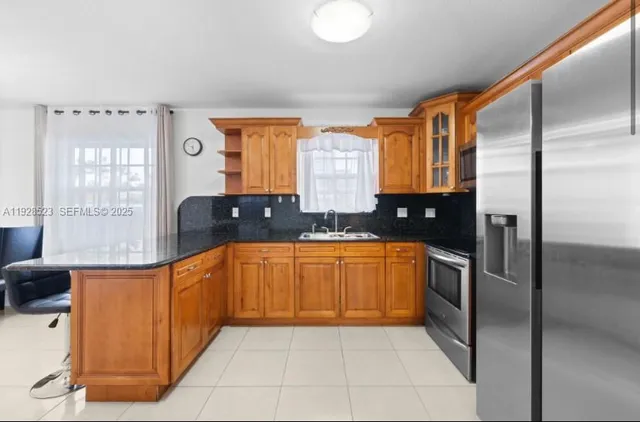 a large kitchen with stainless steel appliances granite countertop a refrigerator and a sink
