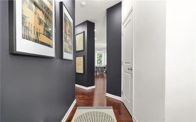a view of a hallway with wooden floor and a bathroom