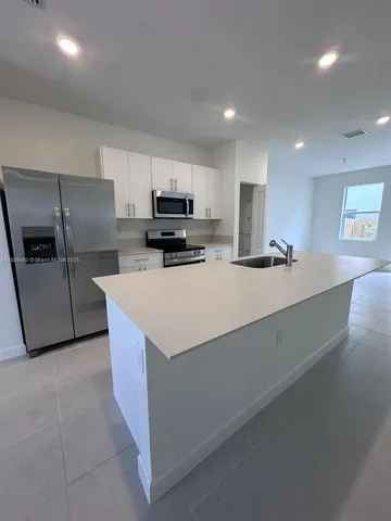 a large kitchen with kitchen island a sink a stove a refrigerator and a cabinets