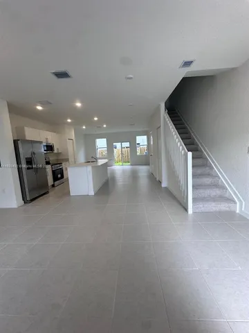 a view of empty room with kitchen and window